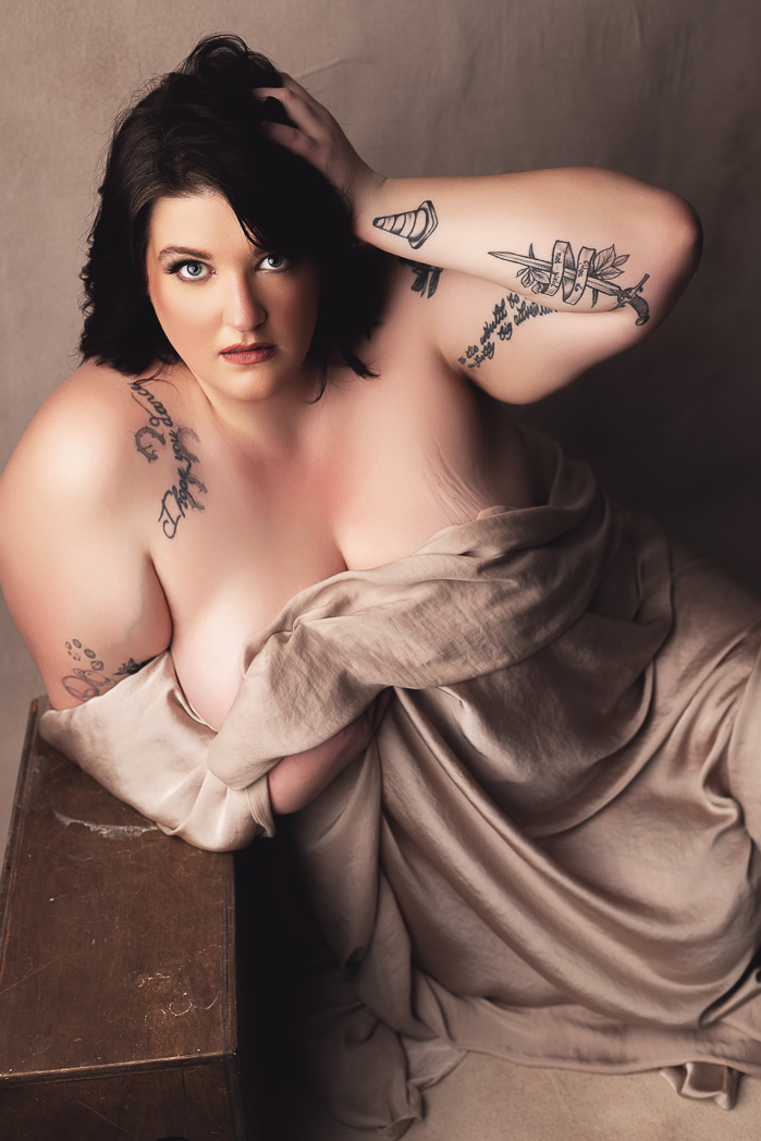 plus sized woman beautifully draped in a champagne colored silk sheet