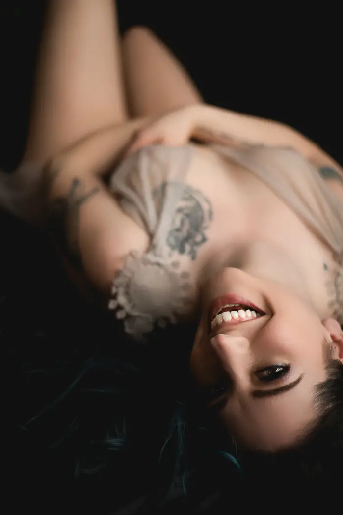 woman in a tan robe posing on a black boudoir bed