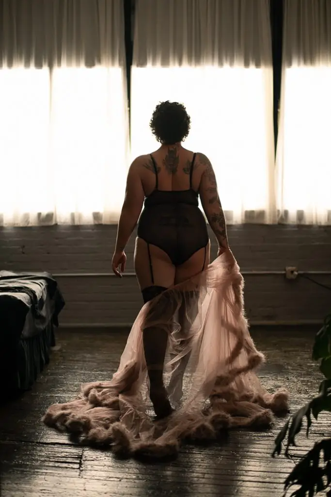 Bestie Boudoir Session: Back view of a girl in lingerie as she's walking away and dropping a flowing piece of the outfit. Syracuse, NY Studio.